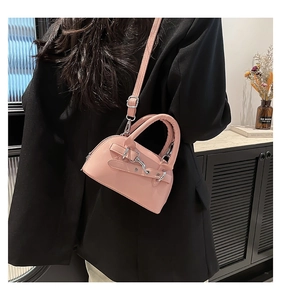 Detail of pink shell-shaped crossbody bag with decorative silver chains and buckles