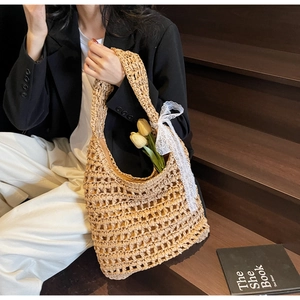 Detail of hollow woven straw tote bag featuring delicate white lace bow decoration