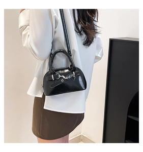 Close-up of black patent leather shell bag with silver hardware and smooth glossy finish