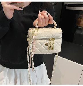 Détail du sac boîte beige matelassé avec bijou camélia et décoration de foulard en soie