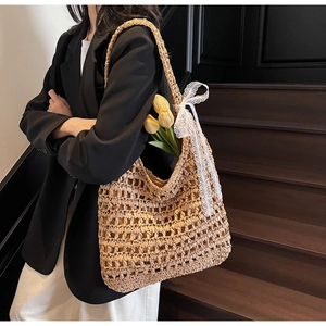 Detail of hollow straw tote bag featuring white lace bow and yellow tulip decoration