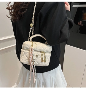Détail du mini sac matelassé avec chaîne à boule dorée réglable porté par le mannequin
