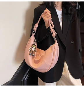 Detail of pink hobo bag with knotted strap and cute charm on荔枝 grain leather