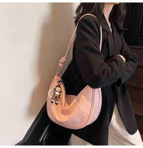Pink crescent tote bag with knot strap and cute bear charm shown on model shoulder