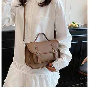 Detailed view of brown lychee texture leather satchel with silver buckles and handle