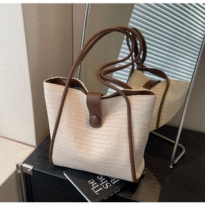 Detailed texture of woven straw tote bag with brown leather trim and mirror reflection