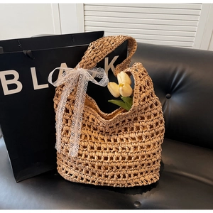 Detailed view of handmade woven straw tote bag with delicate white lace bow and tulips