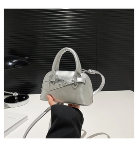 Detail view of a silver shell bag with metallic finish and adjustable shoulder strap