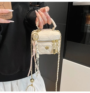 Détail du mini sac boîte matelassé beige avec boucle camélia dorée et bandoulière chaîne