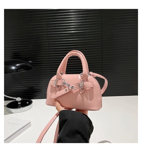 Detail of pink patent leather shell bag with buckle strap and thin shoulder strap