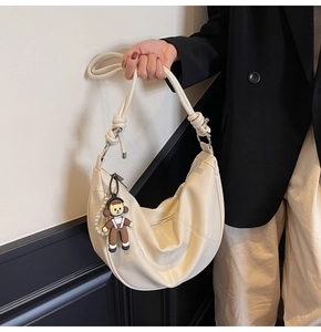 Detail of off-white dumpling tote bag with knotted strap and pearl doll charms