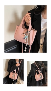 Detail of pink litchi grain leather bucket bag with cute bear charm and shoulder strap