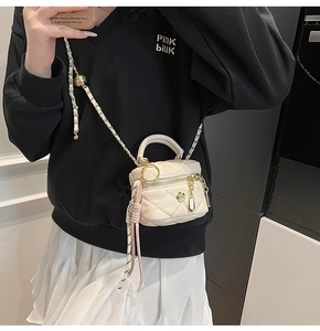 Détail du sac boîte beige matelassé avec chaîne dorée ajustable et fermoir rose
