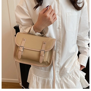 Detail of vintage beige messenger bag with lychee texture and silver metal buckles