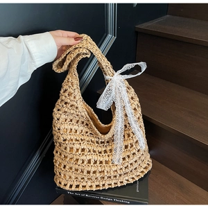 Detail of hand-woven straw tote with hollow pattern and delicate white lace bow decoration