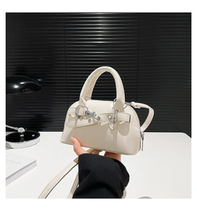Detail view of cream shell crossbody bag with metal ring buckle and smooth handle