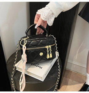 Détails d'un mini sac matelassé noir avec camélia doré et pompon tissé