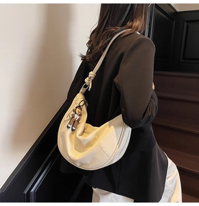 Detail view of off-white lychee texture leather hobo bag with unique knotted strap design