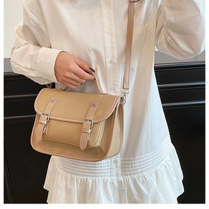 Detail of a beige vintage messenger bag showing lychee texture and buckle closure
