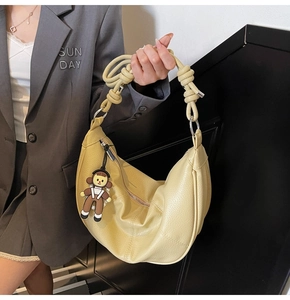 Detail of light yellow soft leather hobo bag with unique spiral knotted shoulder strap