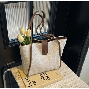 Close-up of woven tote bag with brown leather trim and magnetic closure on books