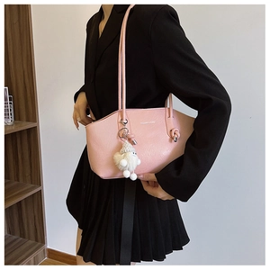 Detail of light pink faux leather bag with lychee texture and cute plush toy charm