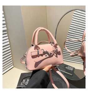 Close-up of pink mini shell handbag with glossy finish and silver metal buckle details