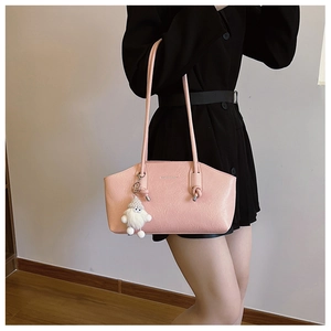 Detail of pink PU leather tote with shoulder straps, metal logo, and a plush charm accessory