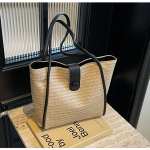 Detail shot of the contrast woven texture and black leather strap on a straw tote bag