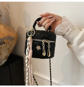 Détail d'un mini sac matelassé noir avec fleur dorée et bandoulière en chaîne
