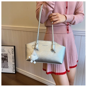 Close-up of silver textured tote bag with pleated finish and white plush charm detail