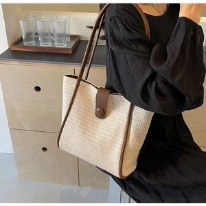 Detail of the woven texture and brown leather strap on this cream tote bag