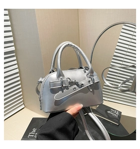 Detail of silver metallic handbag with smooth leather texture and decorative metal buckle
