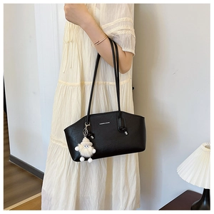 Close-up of black PU leather tote bag with white plush charm and fashion brand logo text