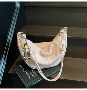 Pink lychee grain leather hobo bag with cute charm detail on wooden background