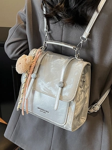 Silver metallic textured backpack for women with a plush bear charm on grey suit