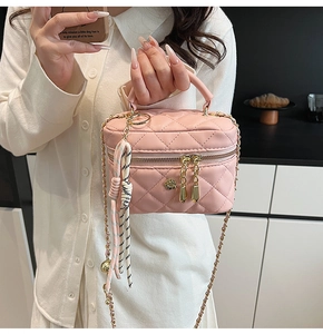 Détail du sac boîte rose matelassé avec bandoulière chaîne, porté par un mannequin