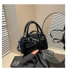 Close-up of a glossy black shell bag with silver metal buckle and shiny synthetic leather