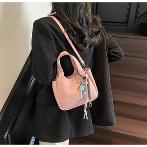 Detail of pink lychee leather bucket bag with top handle and detachable strap on stairs