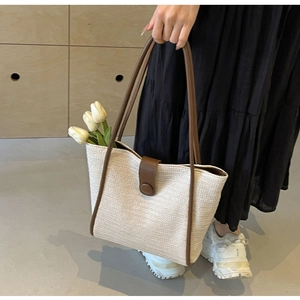 Detail of minimalist woven tote bag featuring deep brown leather trim and round buckle