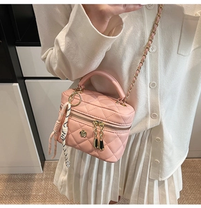 Détail du sac boîte rose matelassé avec logo fleuri doré et bandoulière chaîne