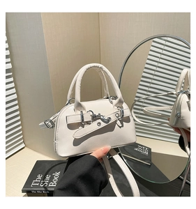 Detail view of cream white leather shell bag with gold buckle and smooth matte finish