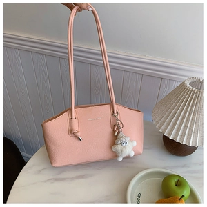 Detail of pink faux leather shoulder bag with FASHION & BAGS print and plush ball charm