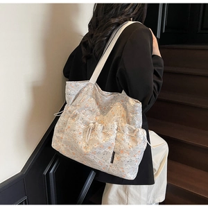 Detail of floral lace tote bag with adjustable drawstring side pocket and woven label
