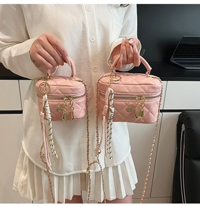 Détail de mini sacs boîte roses en cuir matelassé avec chaîne et breloques florales