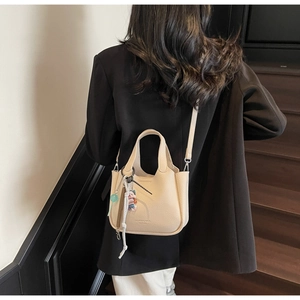 Chic beige lychee leather bucket bag with detachable strap shown in a lifestyle street setting