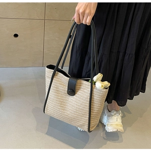 Close-up of beige woven tote bag featuring black leather straps and detailed texture