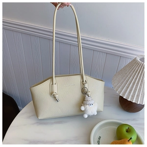 Detail of cream pleated tote bag with thin shoulder straps and plush doll charm
