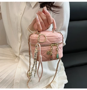 Détail du mini sac cylindre en cuir matelassé rose avec breloque fleur dorée et chaîne
