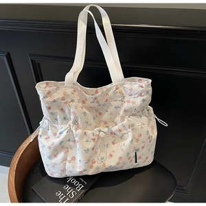 Close-up of floral tote bag showing textured jacquard fabric and side drawstring detail